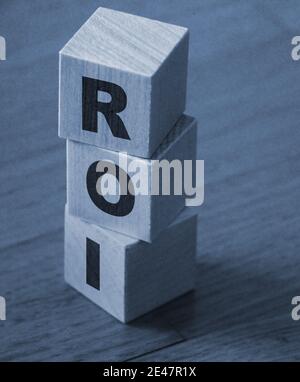 den cubes - letters Pile with three wooROI meaning Return on Investment on them, space for more text at right side. Business concept. Stock Photo