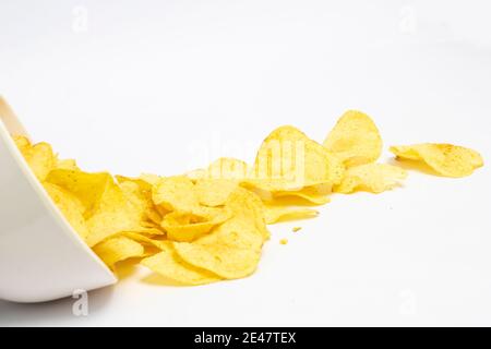 Potato chips falling into bowl isolated on white background Stock Photo