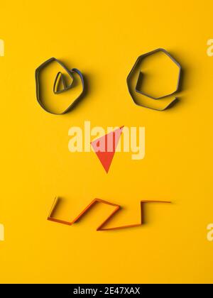 A face made from color paper on yellow background Stock Photo