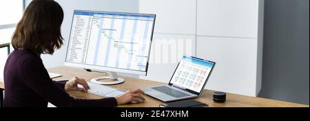 Businesswoman Working On Gantt Chart Using Computer On Office Desk Stock Photo