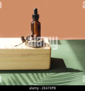 Blank amber glass bottle with face serum on wooden brick. Natural organic cosmetics, herbal essence, sustainable lifestyle concept. Front view, copy s Stock Photo