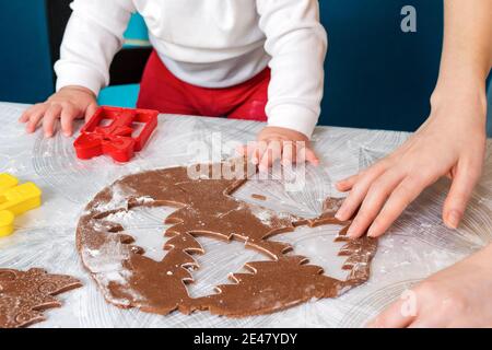 Mother and baby together cut out cookies from the dough. Top view. Close up. Christmas concept and family cooking meals with children. Stock Photo