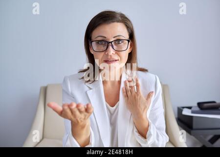 Positive talking middle aged business woman looking at webcam Stock Photo