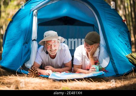 Active lifestyle old senior couple enjoy tent camping in the woods together with love and fun - man and woman retired in outdoor leisure activity in t Stock Photo