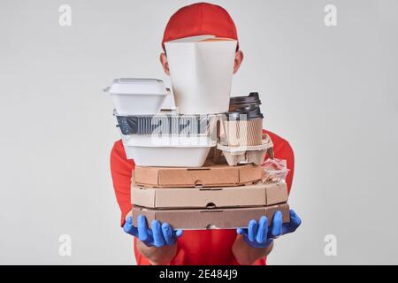 Delivery man holding a huge pile of various packed food Stock Photo
