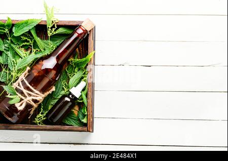 Glass bottle of nettle essential oil with fresh nettle leaves on wooden background Stock Photo