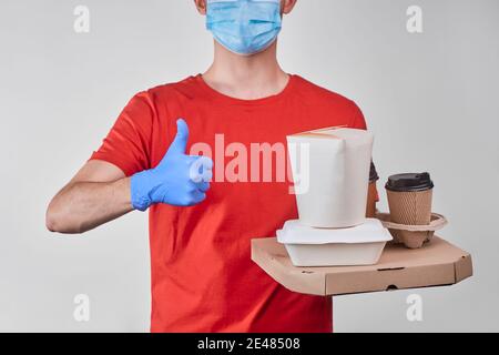 Delivery man holding a pile of ordered food and showing a thumb up Stock Photo