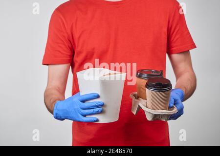 Delivery man holding a box of wok noodles and cups of coffee Stock Photo