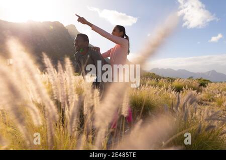 Fit african american couple in sportswear resting leaning on knees in tall grass Stock Photo