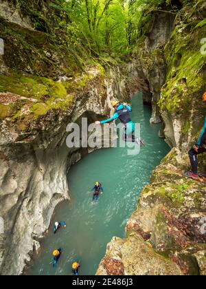 Whitewater sports, canyoning at the “Pont du diable” (Devil's Bridge), in the Giffre Valley. Man jumping into the river from the edge of a cliff in Mi Stock Photo