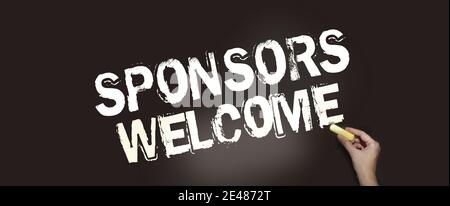 Sponsors welcome phrase handwritten on chalkboard with chalk in a hand. Business startup concept. Stock Photo