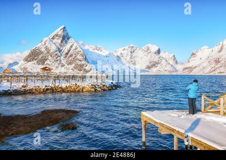 Photographer taking picture of Fantastic panorama of  Reinefjorden on Toppoya island with Olstinden peak. Location: Toppoya island, Lofoten; Norway, E Stock Photo