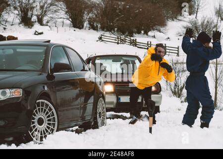 Two friends fighting with snowballs in the snow with the 4wd car on the background Stock Photo