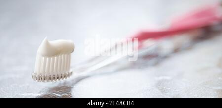Transparent plastic toothbrush with white toothpaste on a glass table with reflection. Stock Photo