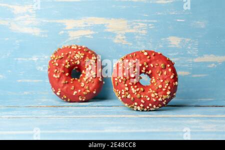 Two red donuts on blue wooden background Stock Photo