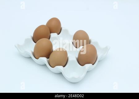 Six brown eggs in an egg rack against a white background Stock Photo