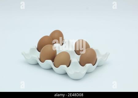 Six brown eggs in an egg rack against a white background Stock Photo