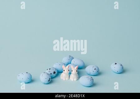 quail blue easter eggs on blue background. Minimal comcept with copy space. spring holidays decor. two white bunnies  Stock Photo