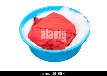Red shirt soaked in washing powders in the plastic basin. Stock Photo
