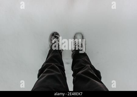 Detail of warm waterproof boots in deep fresh snow.Female feet in black shoes, winter walking in snow.High angle view of standing female legs with sno Stock Photo