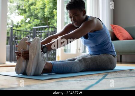 African american woman performing stretching exercise at home Stock Photo