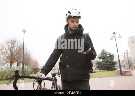 Low angle shot of a male courier using smart phone walking with his bicycle in the city Stock Photo