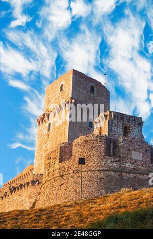Close up view of medieval castle up the hill of Assisi, province in Umbria Italy. Stone bricks tower and walls at evening with clear clouds sky Stock Photo