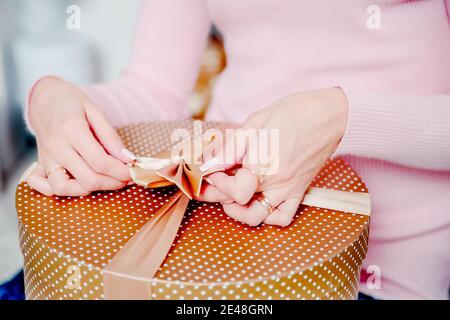A woman ties a box with a gift. Gift packaging. Stock Photo