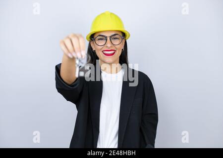 Young architect woman wearing hardhat holding the key of a new house Stock Photo