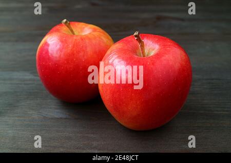 Pair of fresh ripe red apple isolated on dark colored wooden background Stock Photo