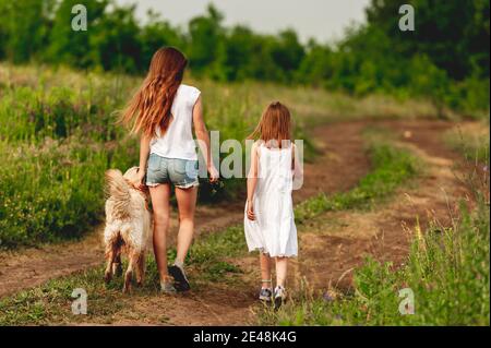Girls walking dog along ground road Stock Photo