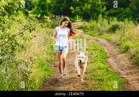 Girl running with dog on nature Stock Photo