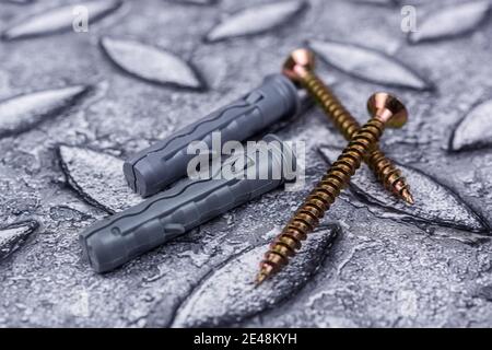 Cross recessed countersunk tapper screws with yellow corrosion coating with appropriate plastic split-ribbed anchors with size marking, close-up in se Stock Photo