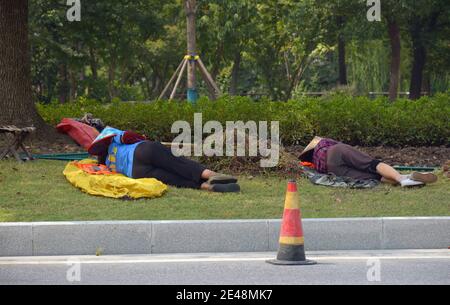 2 ladies working on a street in Jiaxing take a mid day nap before starting afresh after their lunch. Stock Photo