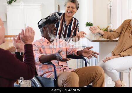 Senior caucasian and african american couples sitting on couch using vr headset at home Stock Photo
