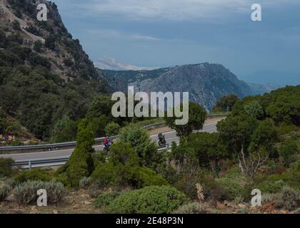 Genna Silana pass, Urzulei, Sardinia, Italy, September 19, Two bikers drive on asphalt road at Genna Silana pass at Supramonte Mountains with white li Stock Photo