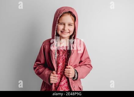 Little girl in pink jacket standing indoors Stock Photo