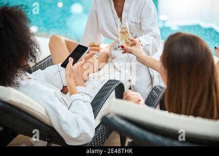 Fragment photo of unrecognised young ladies drinking champagne on poolside Stock Photo