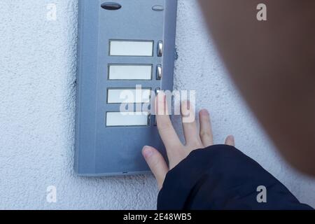 Woman is ringing the doorbell. The female hand presses a button on doorbell. Stock Photo