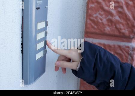Woman is ringing the doorbell. The female hand presses a button on doorbell. Stock Photo