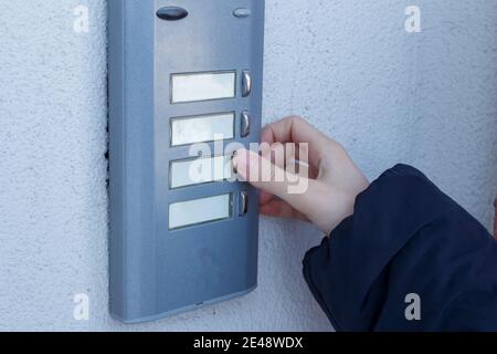 Woman is ringing the doorbell. The female hand presses a button on doorbell. Stock Photo