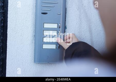 Woman is ringing the doorbell. The female hand presses a button on doorbell. Stock Photo