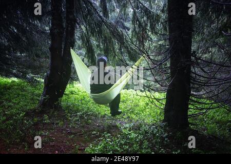 Man on yellow hammock in spring mountains. Travel landscape concept. Outdoor camping Stock Photo