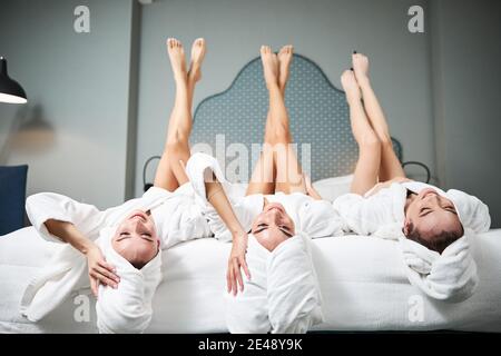Three best lady friends relaxing their feet on the bed Stock Photo