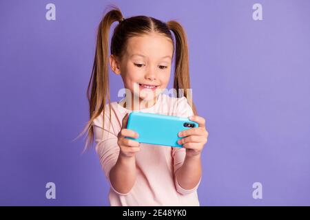 Photo of brown haired pigtails small girl hold play phone wear sweatshirt isolated on violet color background Stock Photo