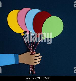 Hand holding a bunch of colorful paper balloons. Balloons party invitation card. Celebrate events banner posters. Holiday, birthday, valentine concept Stock Photo