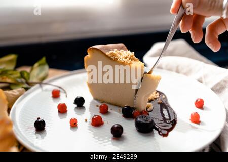 A hand taking a piece of homemade cheesecake with a fork Stock Photo