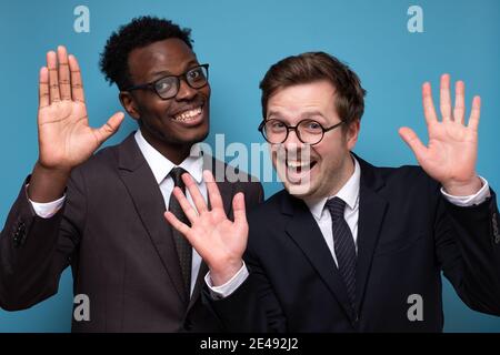 Two caucasian and african men saying hello, waving a hand. Welcome home sign Stock Photo