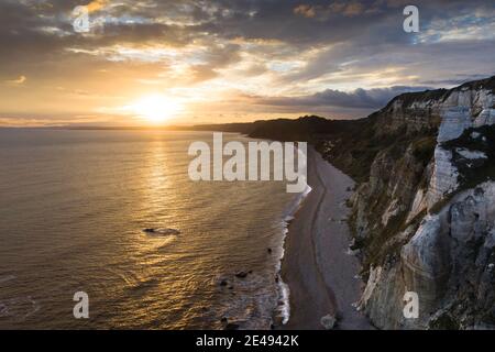 Aerial view of white cliffs, beach and sea taken moments before the sun sets casting light and shadows. Stock Photo