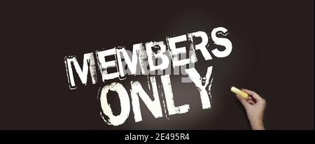 Members Only in pale yellow on blackboard and hand with chalk. VIP special services Business concept. Stock Photo